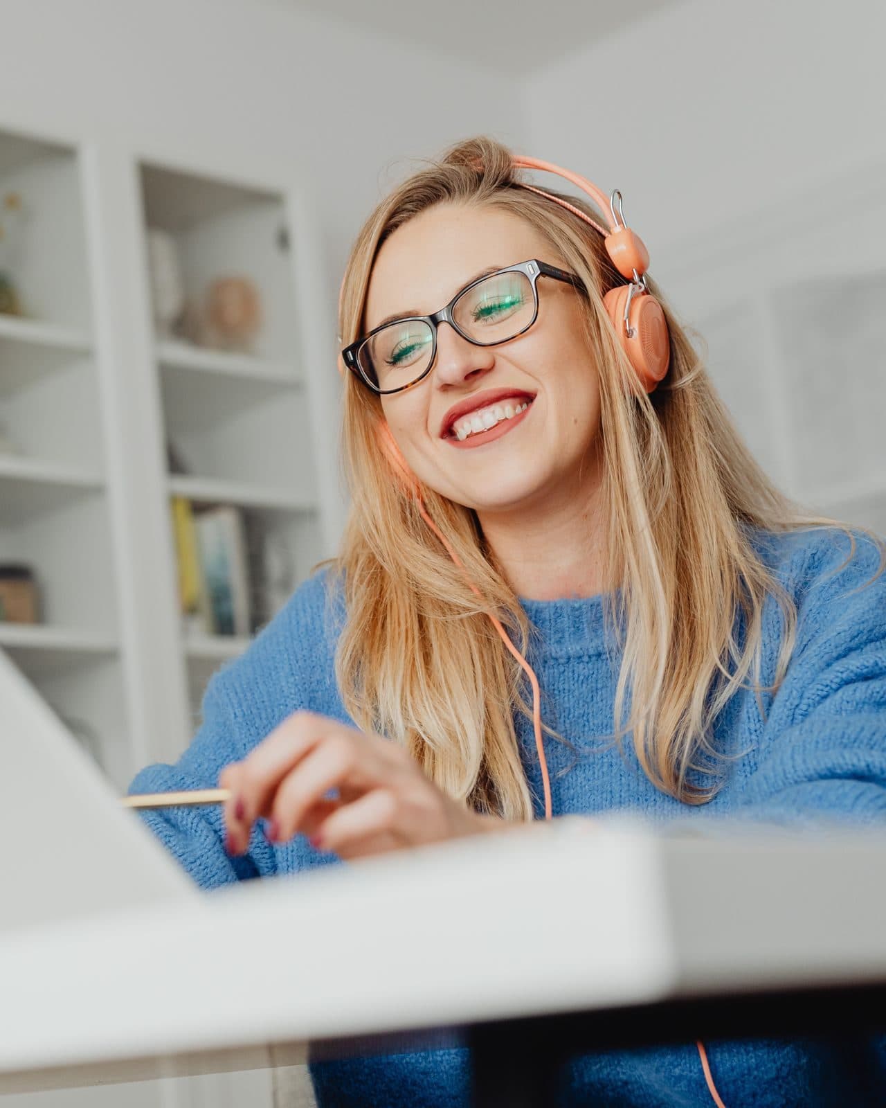 A woman in headphones smiling at her laptop during a video call