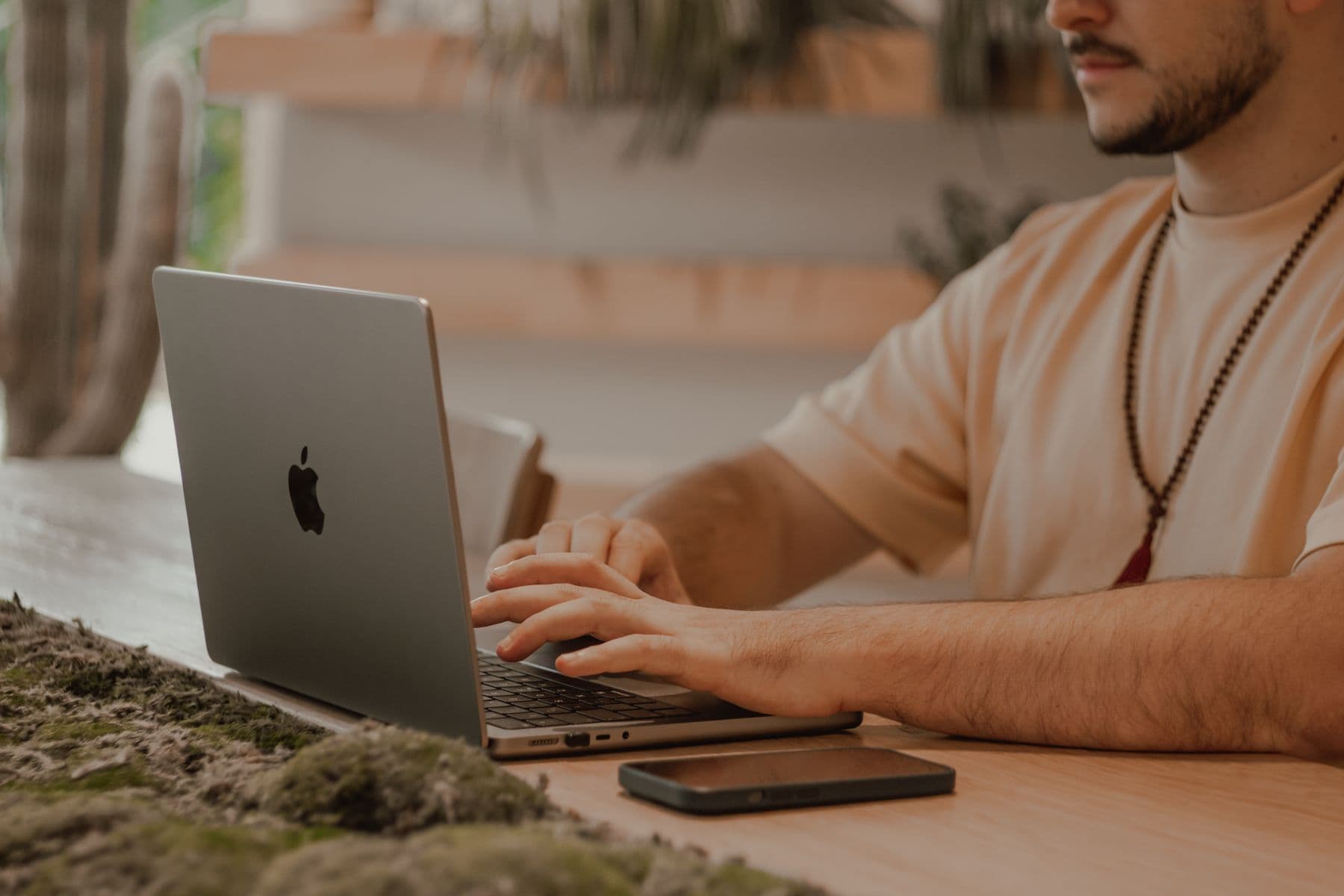 Hands typing on a laptop at a light wooden desk
