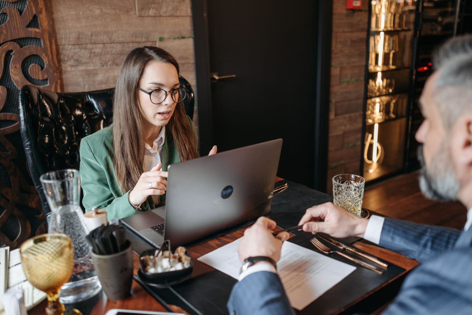 A consultant with a laptop talking with a client over a working lunch