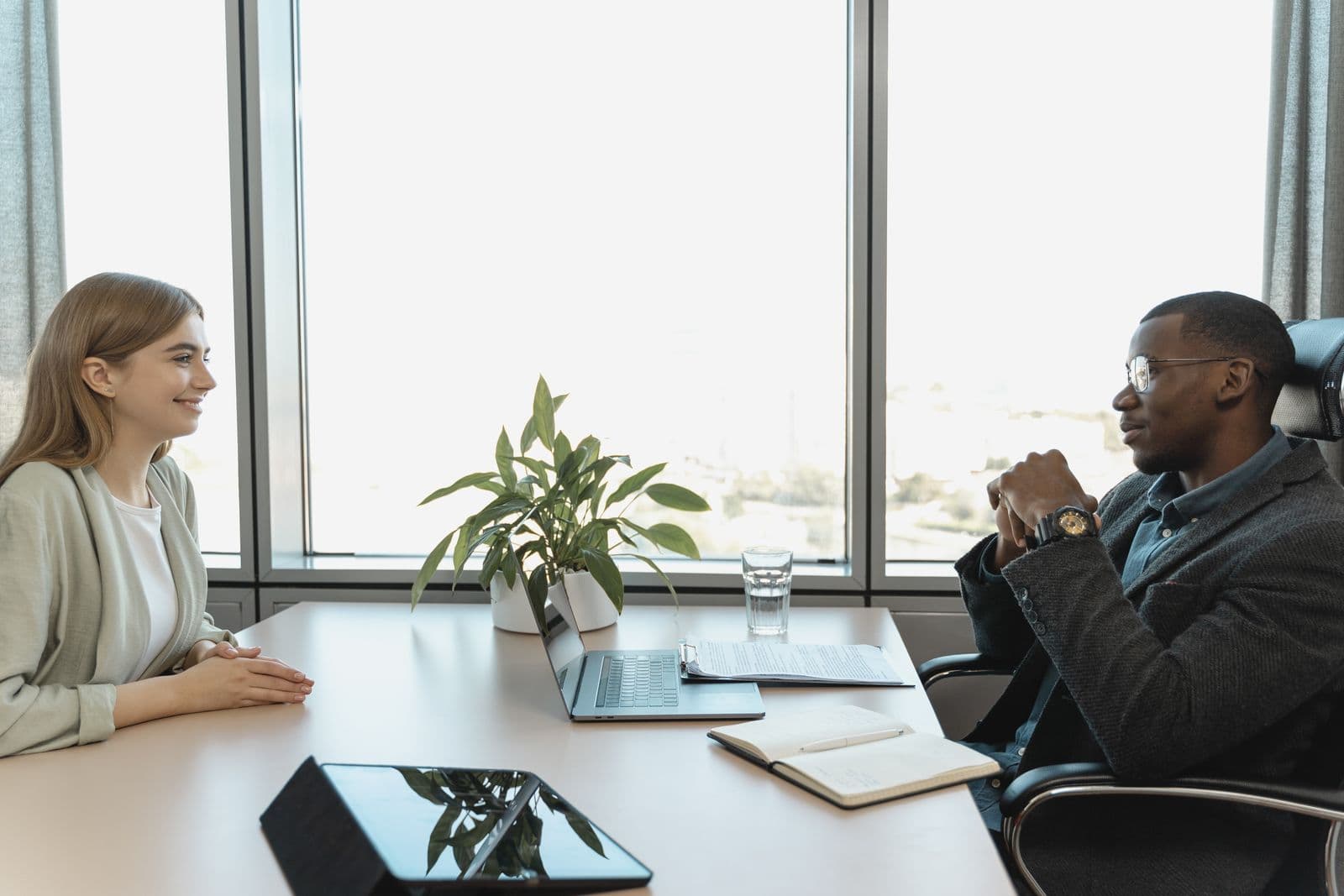 Two people talking across a table in a bright office